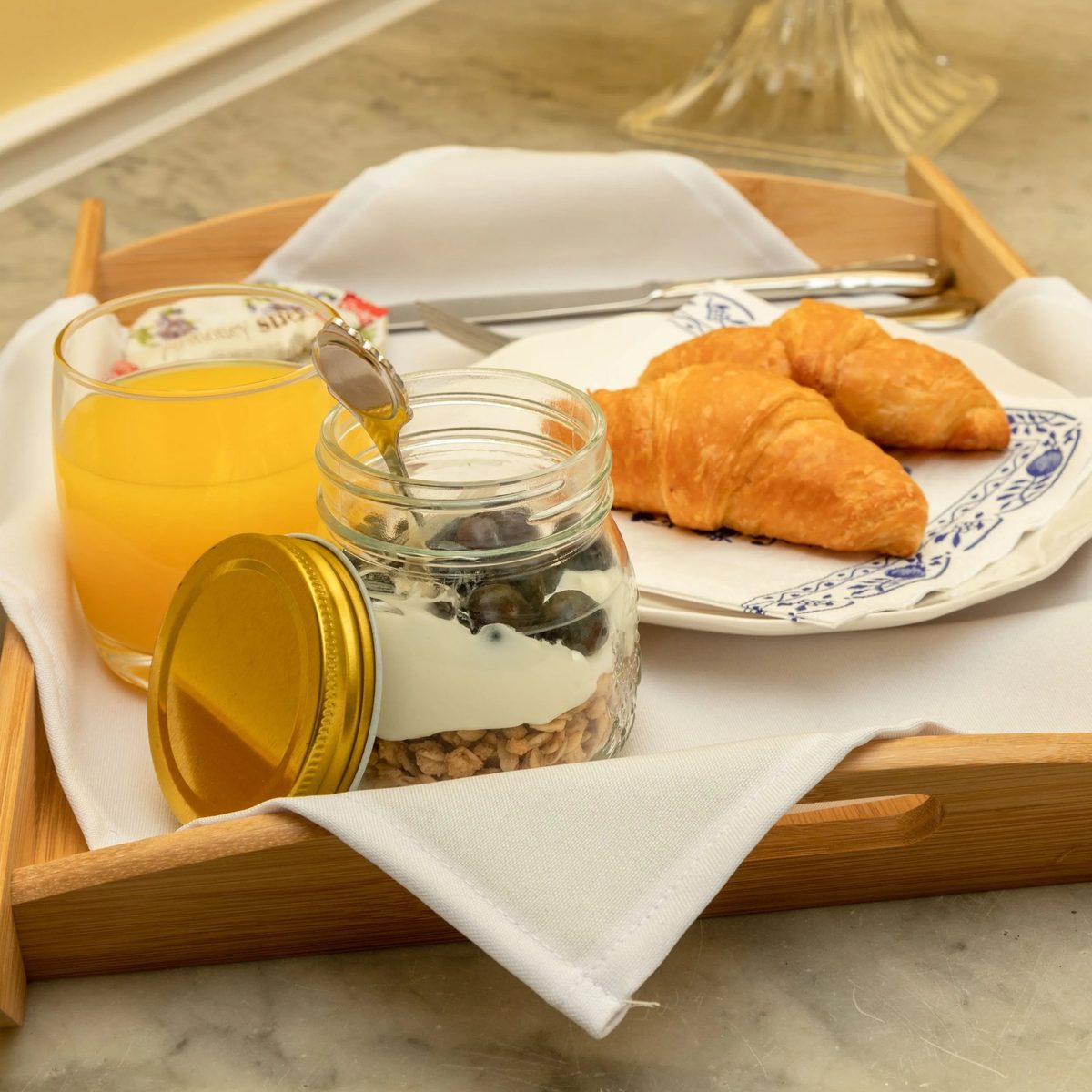 A breakfast tray with croissants, orange juice and a jar of yoghurt