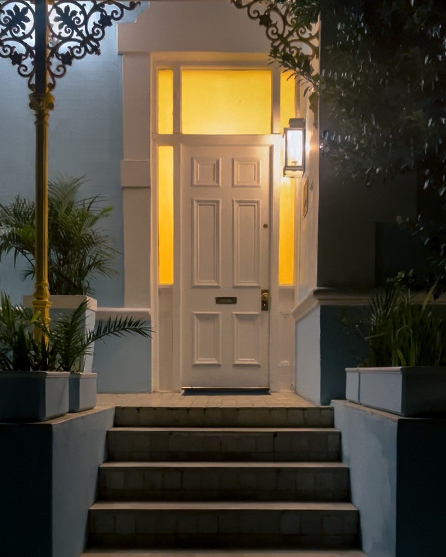 The front door of Amina at night, warm light under the yellow lace