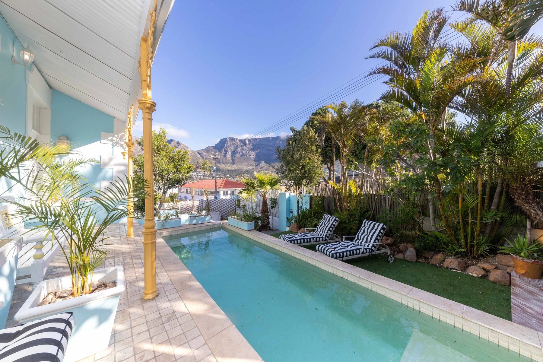 The long pool beside the house, striped loungers and Table Mountain behind