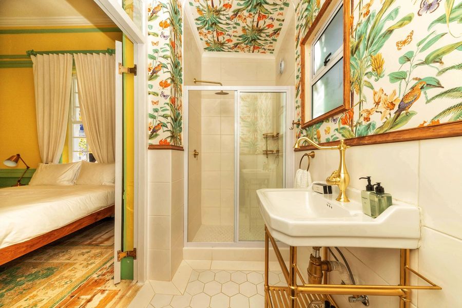 The bathroom with botanical wallpaper and a glass shower