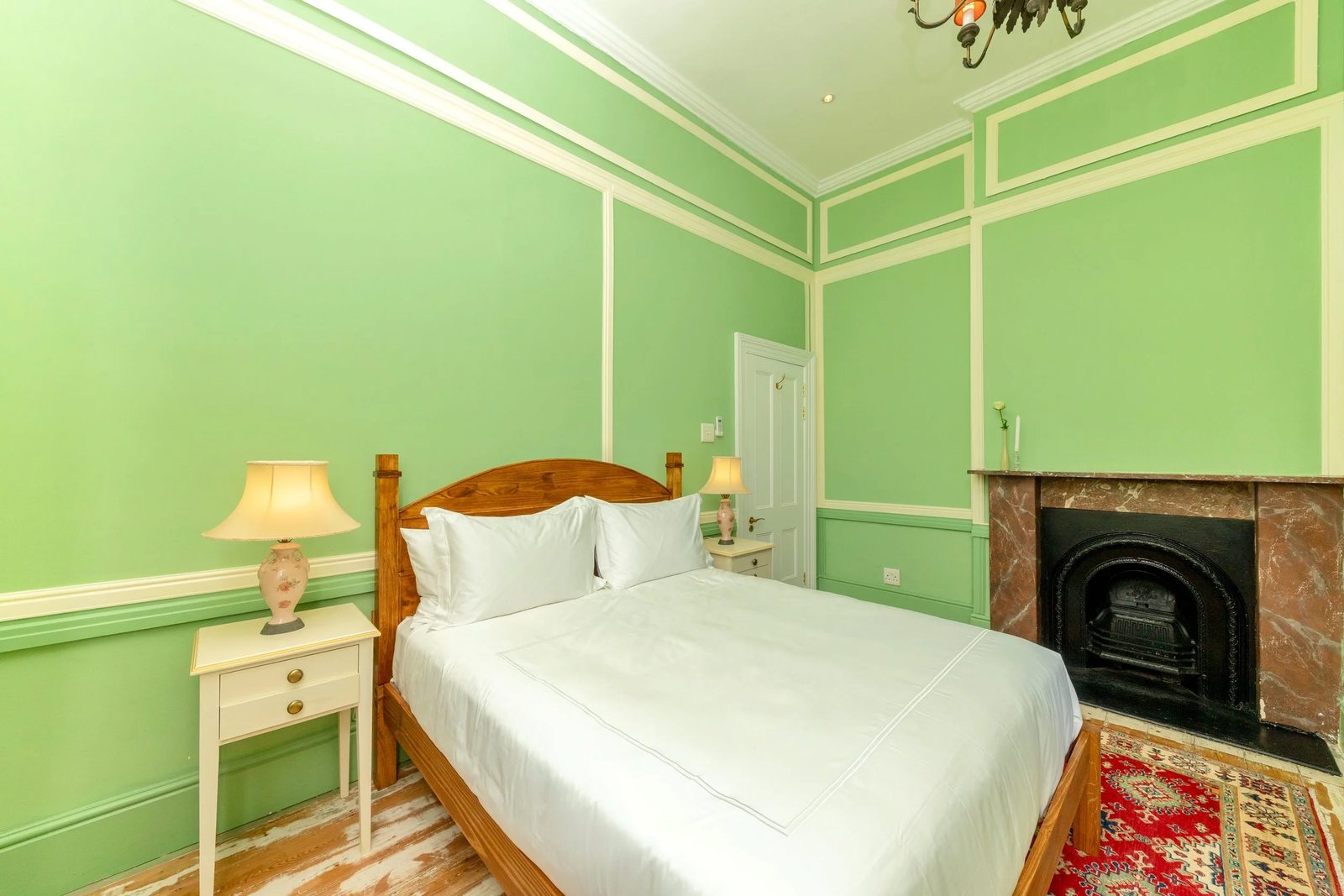 Room 2: pistachio green walls, a cast-iron fireplace and a queen bed