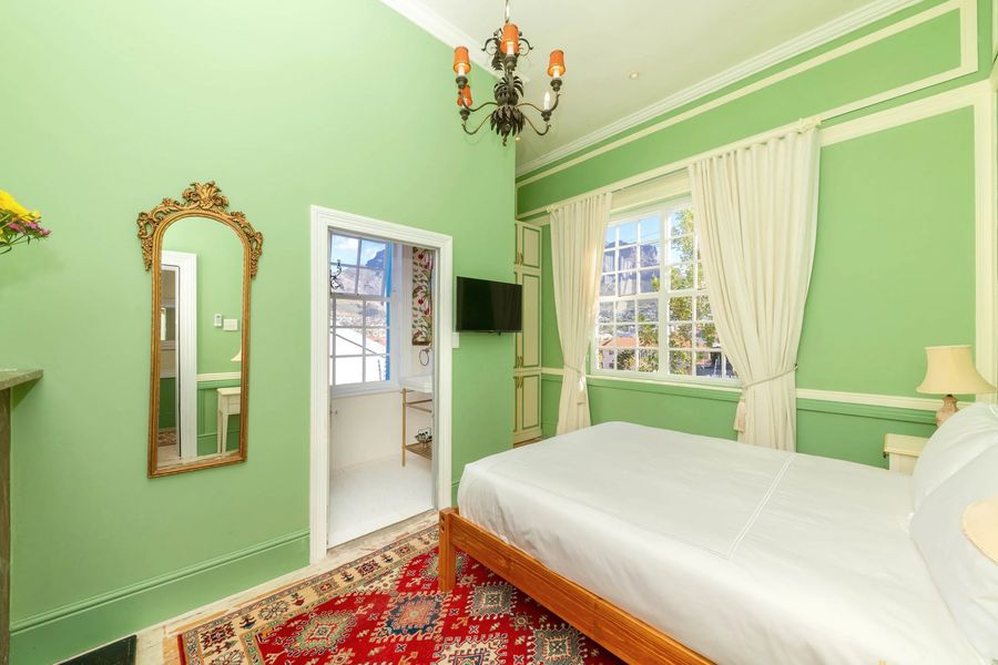 The green room with a gilded mirror and a red Persian rug