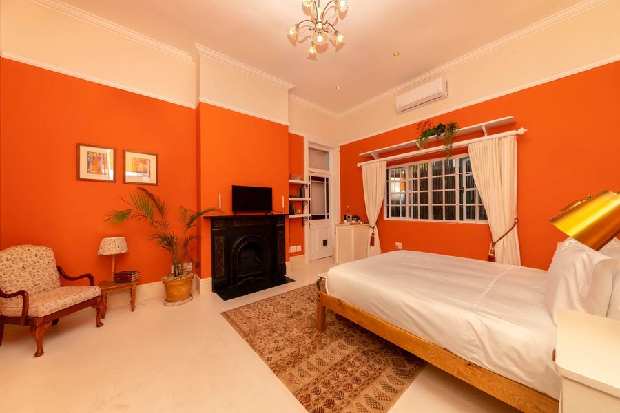 An armchair and a palm beside the fireplace in the orange room
