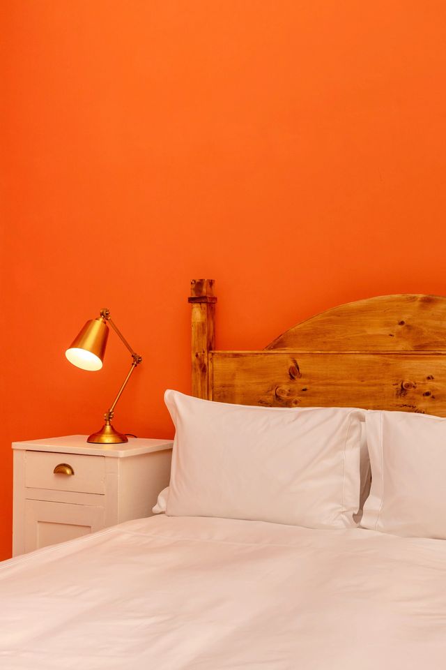 A brass reading lamp against the orange wall